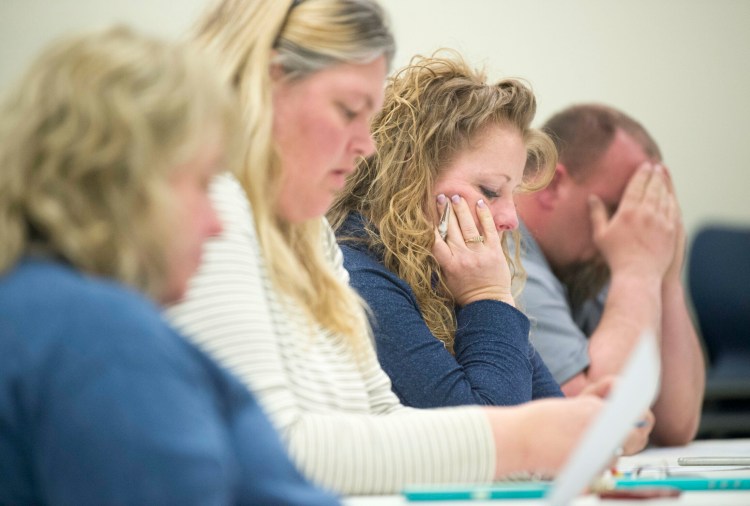 Kara Kugelmeyer, left, Katie Flood-Grow, left center, Katrina Dumont, right center, and Roy White, right, follow along Friday with the meeting notes during a special meeting at Lawrence Middle School in Fairfield. Board members at the special meeting approved settlements with three administrators whose positions were affected under a restructuring plan developed by Superintendent Reza Namin.