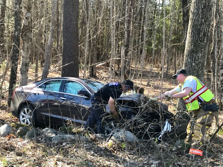 Fire and rescue workers work to remove a car that crashed into a tree Monday on U.S. Route 2 in Pittsfield. The driver of the vehicle was pronounced dead at the scene. 