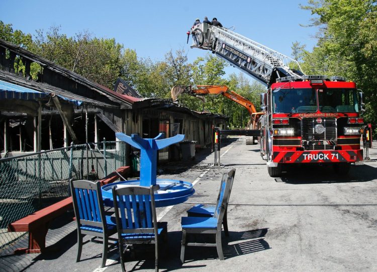 Fire investigators inspect the burned building at Bayley's Camping Resort in Scarborough on Wednesday as an excavator peels back the metal roof.