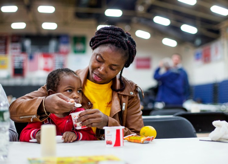 An asylum seeker from Cameroon, who did not want to give her name, feeds her son Thursday at the emergency shelter the city has set up for asylum seekers at the Portland Expo.
