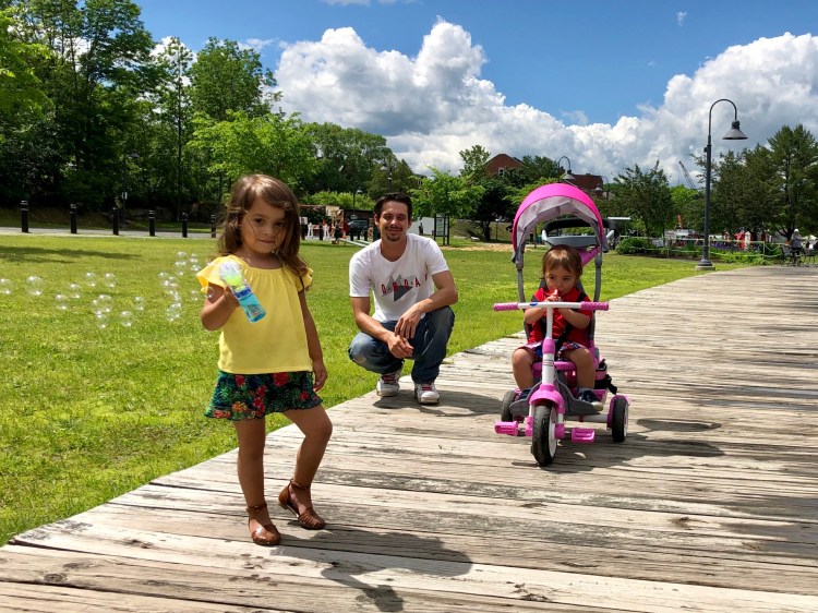 Adelena Wolf, 3, blows bubbles and her brother Wesson, 1, plays a toy trumpet Saturday while father Josh watches them at the Gardiner Waterfront. 