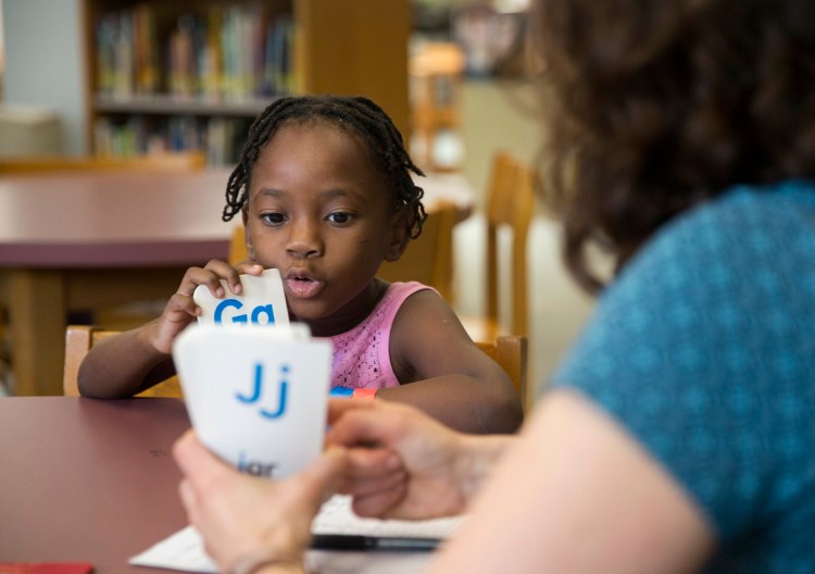 Emily Hall Greeley does an English language assessment with Stela Solani Ndombasi Mvemba, 5, at King Middle School on Wednesday. Ndombasi Mvemba is one of roughly 75 children of asylum seekers who are being processed and assessed by Portland Public Schools. Many of the children will start summer school next week. 