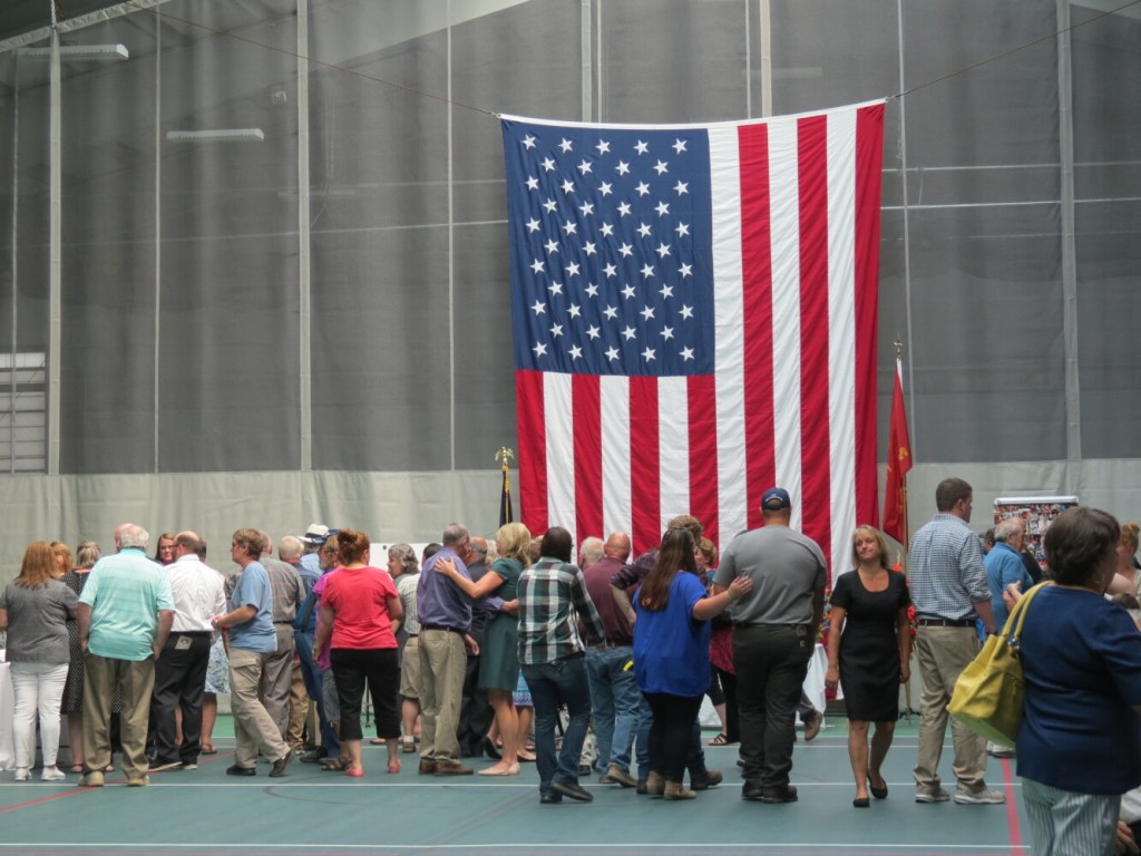 Family and friends of Jim Lane comfort one another Sunday following speeches during the late Fairfield fire captain's celebration of life service in Waterville. 