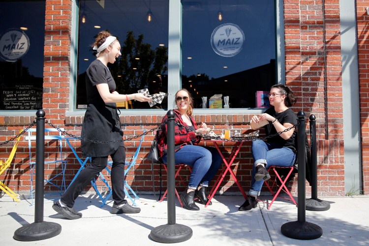 Maiz co-owner Martha Leonard, left, brings an order to Krislyn Stark and Sara Coffill.