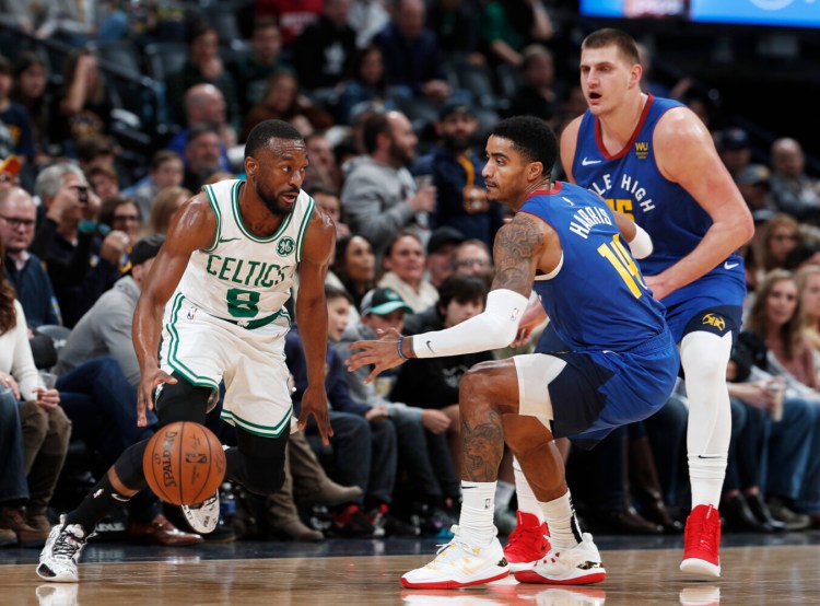 Boston Celtics guard Kemba Walker, left, is defended by Denver Nuggets guard Gary Harris and center Nikola Jokic, right, Friday night in Denver. Walker left the game on a stretcher after he collide with teammate Semi Ojeleye.