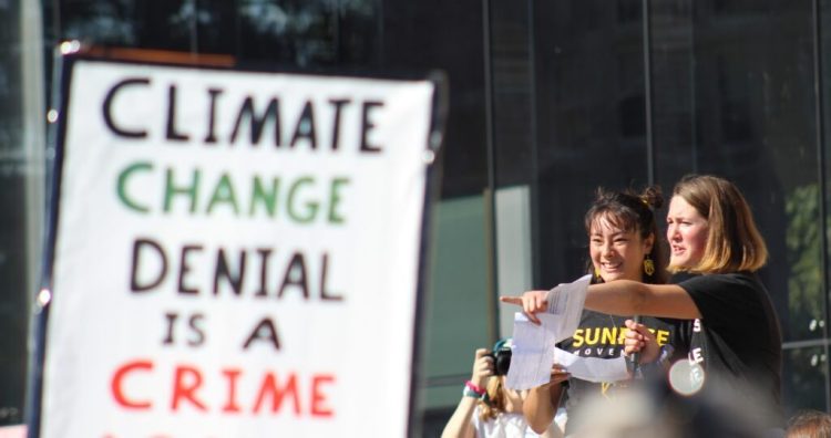 Bowdoin College students Ayana Harscoet (left) and Perrin Milliken lead protesters in a song at Bowdoin College in September.  Students protested  and demanded justice and change in the face of what they called a “climate crisis.