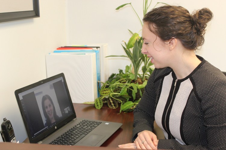 Central Maine Growth Council staff simulate a video chat interview. From left are Kelly Smith and Elaine Theriault-Currier.