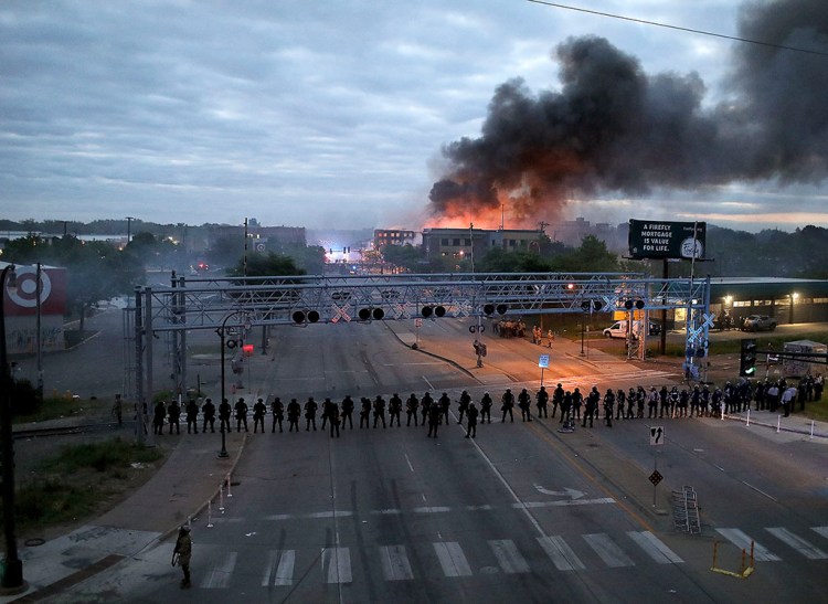 Law enforcement officers amassed in Minneapolis early Friday as fires burned after a night of protests of the death of George Floyd. Floyd died after being restrained by Minneapolis police officers on Memorial Day.
