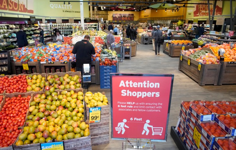 A sign at the entrance to the Hannaford supermarket in Scarborough on March 27, reminds customers to stay six feet apart while shopping in the store. Grocers in Maine and across the U.S. are rebuilding their supply chains after the pandemic disrupted their businesses, first with customers buying up excess supply, followed by viral outbreaks and government-imposed restrictions.