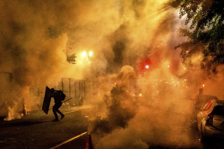 A Black Lives Matter protester uses a shield as federal officers use chemical irritants to disperse demonstrators at the Mark O. Hatfield U.S. Courthouse on Friday in Portland, Ore. 

