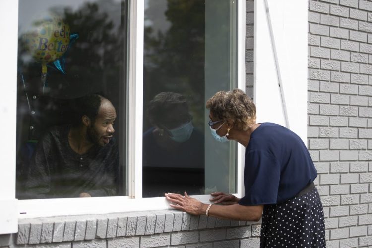 Southern Pines nursing home resident Wayne Swint gets a birthday visit from his mother, Clemittee Swint, in Warner Robins, Ga., in June. At the height of the coronavirus pandemic, the closest many could get to loved ones in nursing homes was waving on the other side of an exterior window.