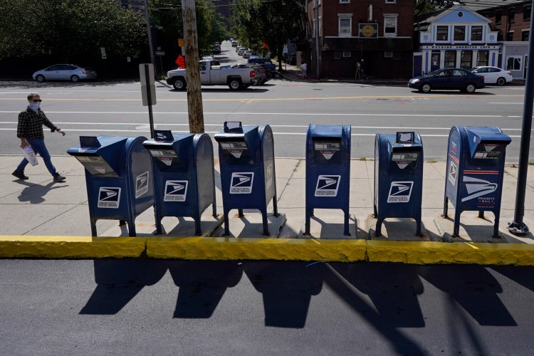 A man walks by a row of U.S. Postal Service mailboxes on his way to the post office, Tuesday, Aug. 18 in Portland.