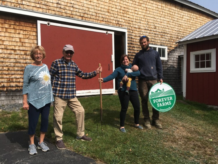 From left are Glenn and Joan Tremblay handing over the family heirloom pitchfork to Emily Eckhardt, Dillon Robinson and their 2-month old son, Woody. 