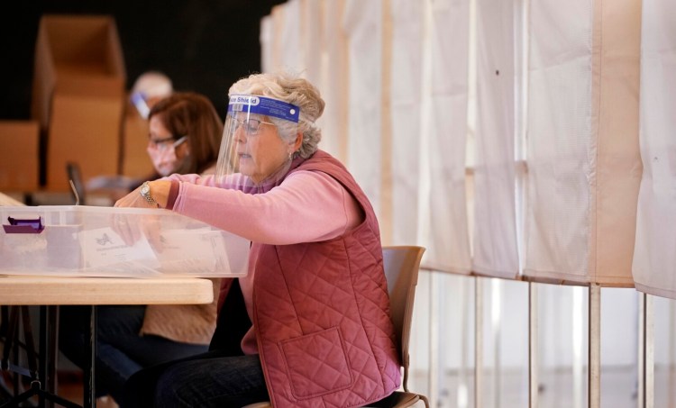 KENNEBUNK, ME - OCTOBER 31: Becky Beers reads names on absentee ballot envelopes as another election worker verifies them on a list at Kennebunk Town Hall on Saturday, October 31, 2020. (Staff Photo by Gregory Rec/Staff Photographer)