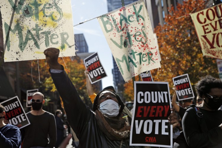 Zhanon Morales, 30, of Philadelphia raises her fist Wednesday as demonstrators call for all votes be counted during a rally outside the Pennsylvania Convention Center in Philadelphia, as vote counting in the general election continued. 

