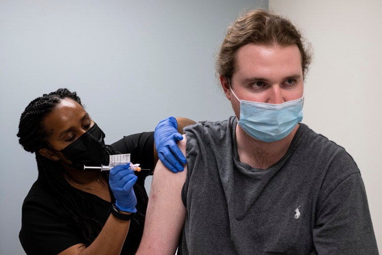 Cole Smith receives a Moderna variant vaccine shot from clinical research nurse Tigisty Girmay at Emory University's Hope Clinic, on Wednesday afternoon, March 31, 2021, in Decatur, Ga. Smith, who received Moderna's original vaccine a year ago in a first-stage study, said returning wasn’t a tough decision. “The earlier one, it was a great success and, you know, millions of people are getting vaccinated now. ... If we’re helping people with the old one, why not volunteer and help people with the new one?” (AP Photo/Ben Gray)