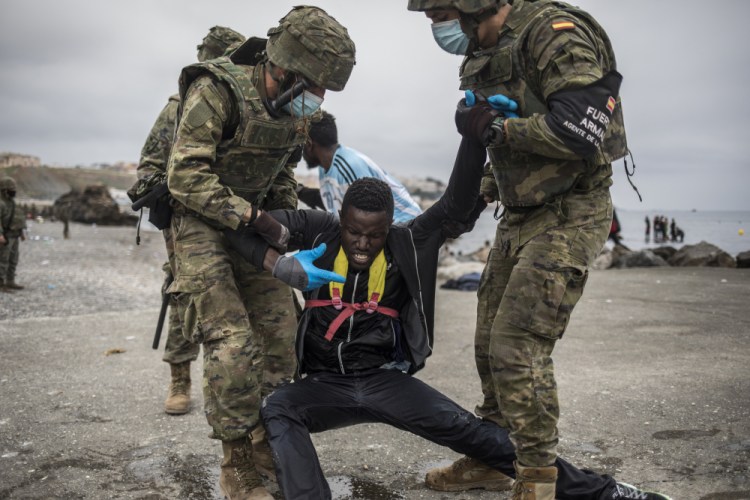 A man is held by soldiers of the Spanish Army at the border of Morocco and Spain, at the Spanish enclave of Ceuta, on Tuesday. Around 6,000 people had crossed by Tuesday morning since the first arrivals began in the early hours of Monday, including 1,500 who are presumed to be teens. 