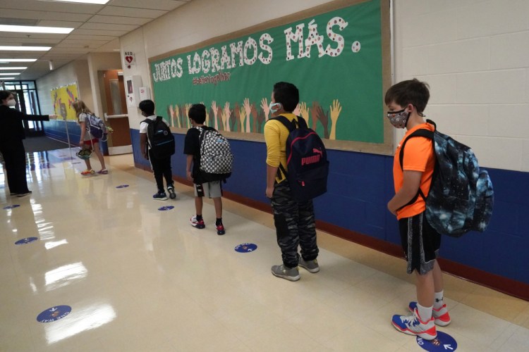 Students keep social distance as they walk to their classroom Sept. 3, 2020, in Highwood, Ill., part of the North Shore school district.