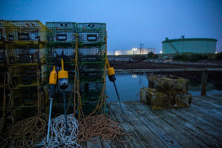 Lobster traps stacked on the Portland Street Pier frame oil tanks near Front Street in South Portland on Wednesday. South Portland won a lawsuit brought by the Portland Pipe Line Corp., ending more than six years of federal litigation over a local law that effectively prevents the company from reversing the flow of its defunct World War II-era oil pipeline to bring crude from Canada to Maine.