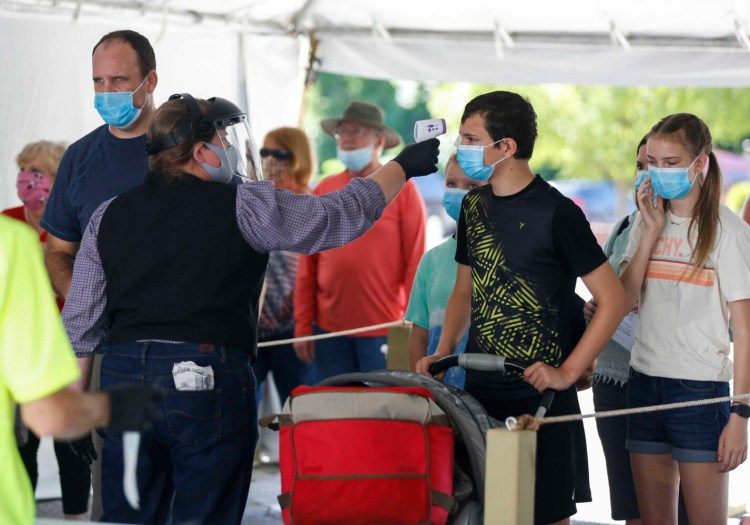 FILE - In this June 13, 2021, file photo, a Silver Dollar City employee takes the temperature of guests before they are allowed to enter the park just west of Branson, Mo. Missouri's health department is reporting the highest daily count of new COVID-19 cases since the dead of winter, and the association representing the state's hospital has warned that the health care system is potentially on the brink of a crisis. (Nathan Papes/The Springfield News-Leader via AP, File)