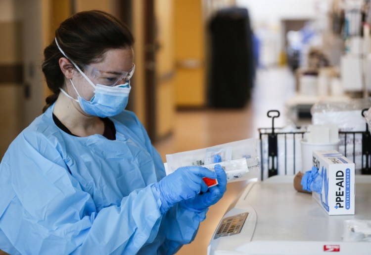 Nurses and doctors in the CoxHealth Emergency Department in Springfield, Mo., don personal protective equipment to treat patients with COVID-19 on Friday. Southwest Missouri is seeing a surge in delta variant cases, with hospitals nearing capacity and requesting help from the state for staffing and an alternative care site.