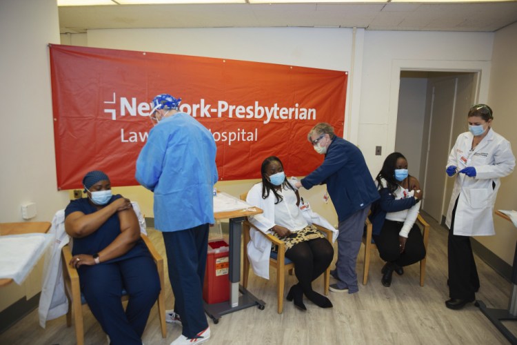 Doctors inject sisters Claudia Scott-Mighty, left, and Althea Scott-Bonaparte, who are patient care directors, and Christine Scott, an ICU nurse, with their second shot of the Pfizer vaccine at NewYork-Presbyterian Lawrence Hospital, in Bronxville, N.Y. , in January. Workers in New York City-run hospitals and health clinics will have to get vaccinated or get tested weekly under a policy announced Wednesday to battle a rise in COVID-19 cases fueled by the highly contagious delta variant. 