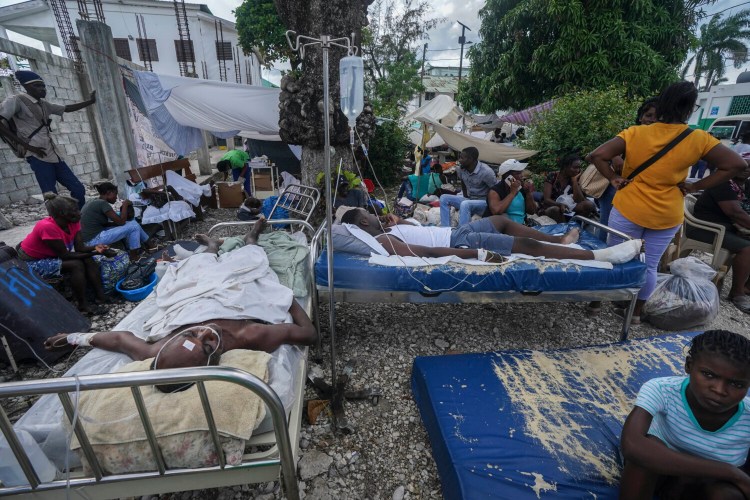 Injured people lie in beds outside the Immaculée Conception hospital in Les Cayes, Haiti, Monday, Aug. 16, 2021, two days after a 7.2-magnitude earthquake struck the southwestern part of the country. (AP Photo/Fernando Llano)