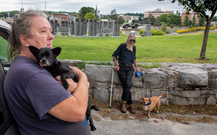 Ann Rivers holds her dog, Gizmo, as she and her husband Paul relax in Veterans Memorial Park in Lewiston Friday afternoon. They have been frustrated trying to find a safe and affordable apartment to live in the twin cities. Their two service dogs, Gizmo and Milky Way, are friendly and well trained but they feel they may be the reason some of the landlords they talked to wouldn't call them back.