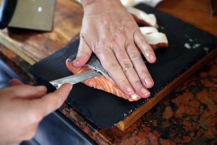 BRUNSWICK, ME - SEPTEMBER 23: Christine Burns Rudalevige skins a portion of farm-raised salmon. (Staff photo by Ben McCanna/Staff Photographer)