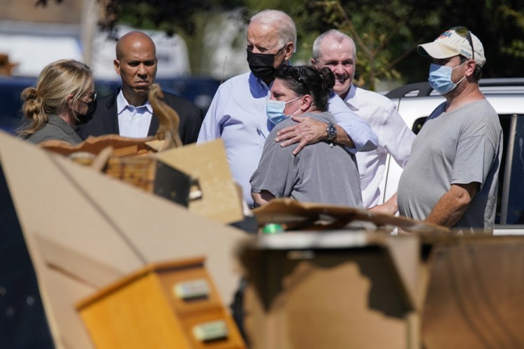 President Joe Biden hugs a person as he tours a neighborhood impacted by Hurricane Ida, Tuesday, Sept. 7, 2021, in Manville, N.J. Sen. Cory Booker, D-N.J., second from left, and New Jersey Gov. Phil Murphy, second from right, look on. 