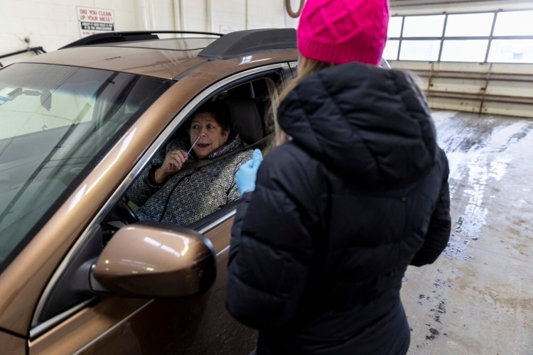 Janet Cowen self-administers a rapid COVID-19 test before handing it back to Daniela Pinto at Yarmouth Public Works on Monday. 