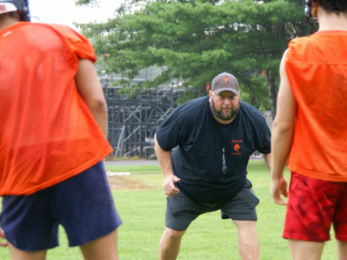 Mark Renna, head coach of Brunswick football, teaches proper linebacker technique during the first day of practice on Monday, Aug. 19, 2024.